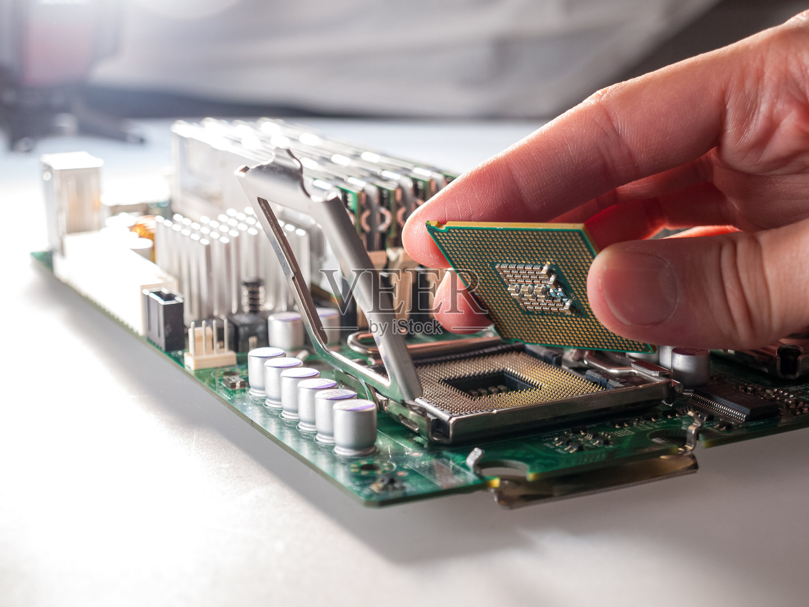 将CPU连接到现代计算机主板上的处理器插座，取代硅数据处理芯片，并正确安装中央处理单元的过程照片摄影图片