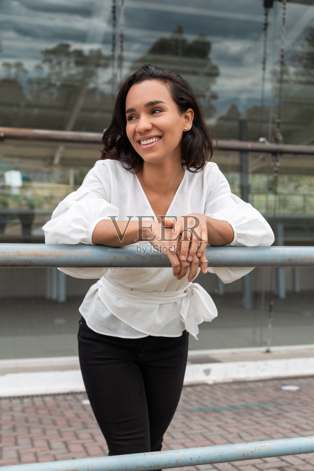 年轻的深色头发的拉丁女人倚着扶手照片摄影图片