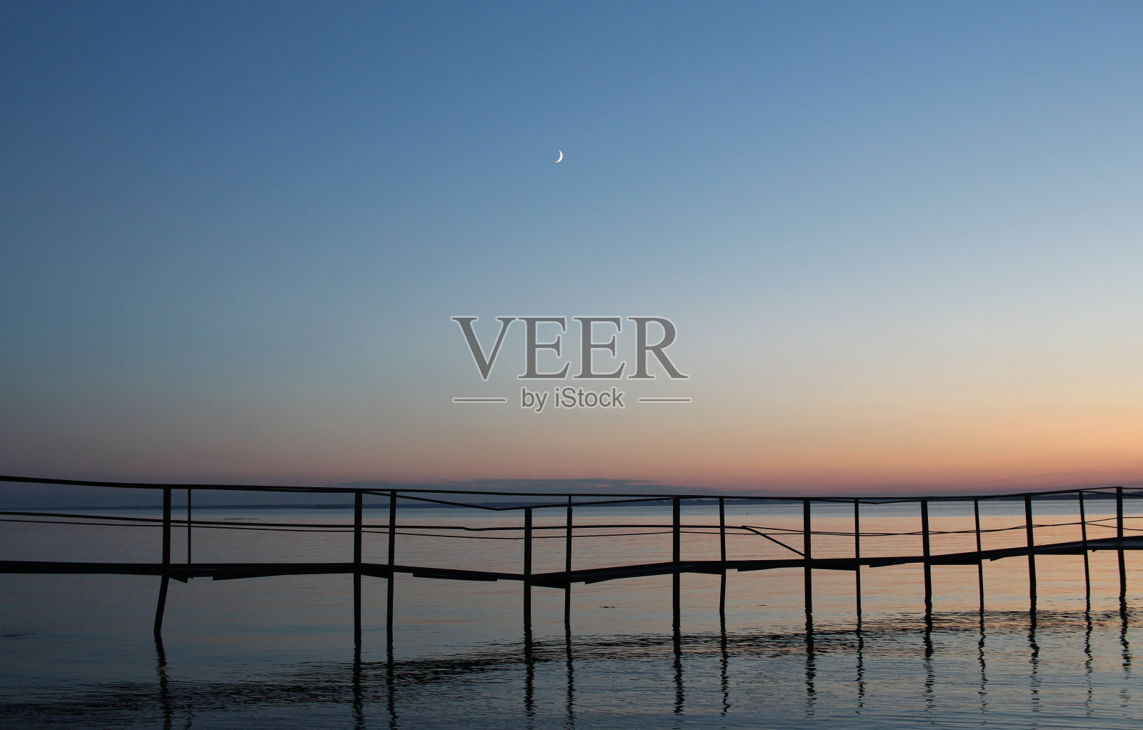 日落在海上，傍晚在码头上风景如画照片摄影图片