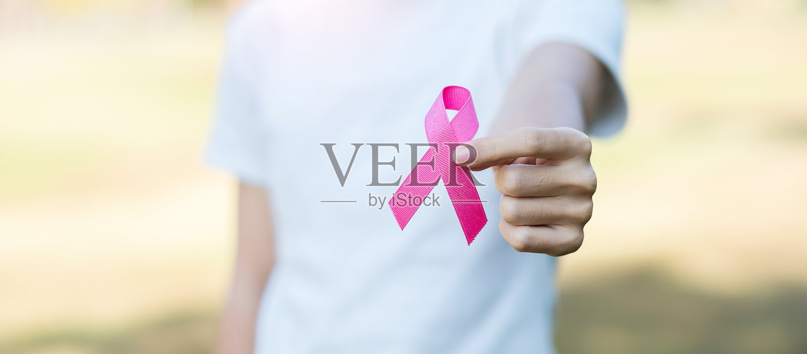 十月乳腺癌宣传月，成年妇女手握粉红丝带支持人们生活和疾病。国际妇女、母亲和世界癌症日的概念照片摄影图片