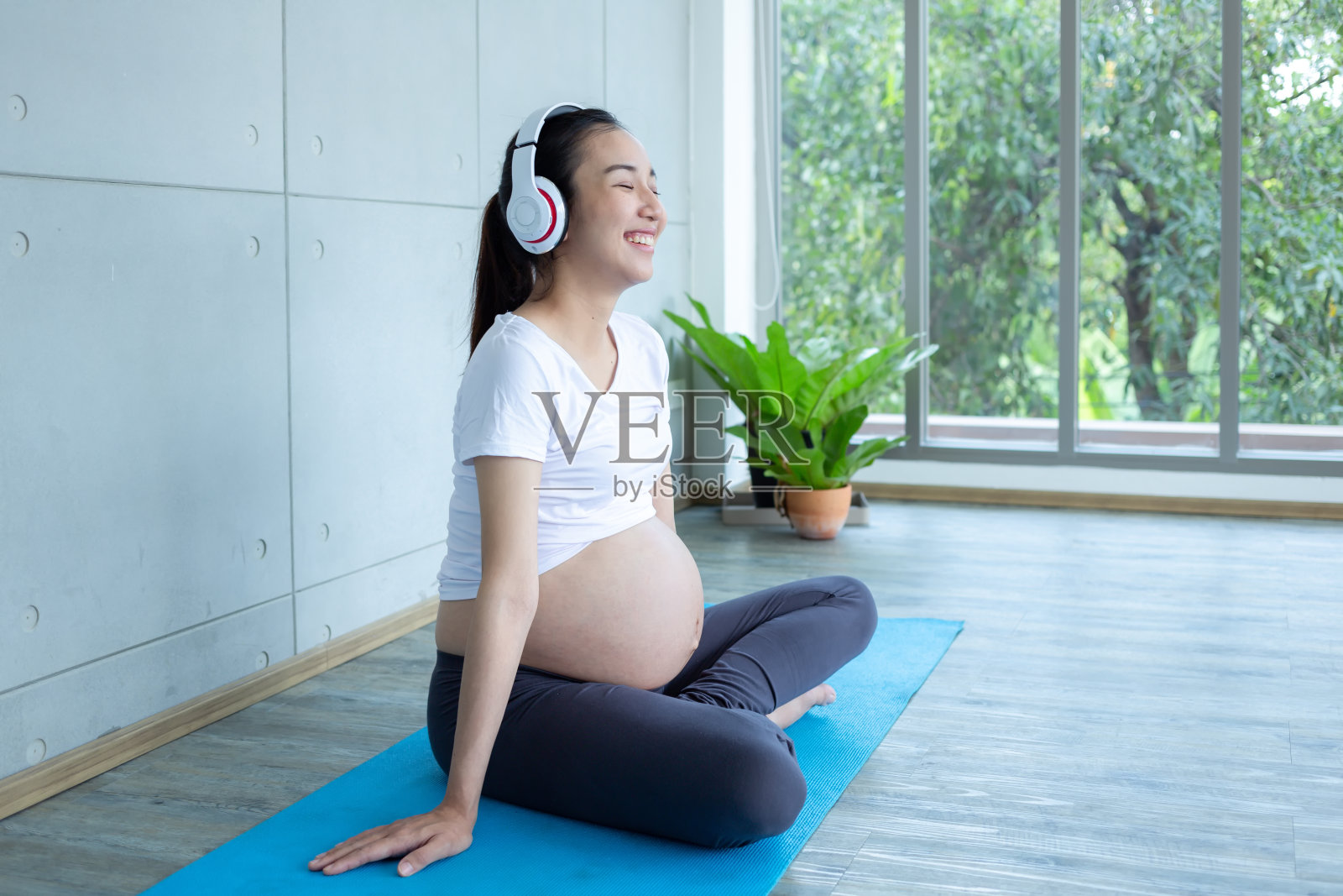 打开音乐，让宝宝放松。孕妇坐着，把耳机放在肚子上。照片摄影图片