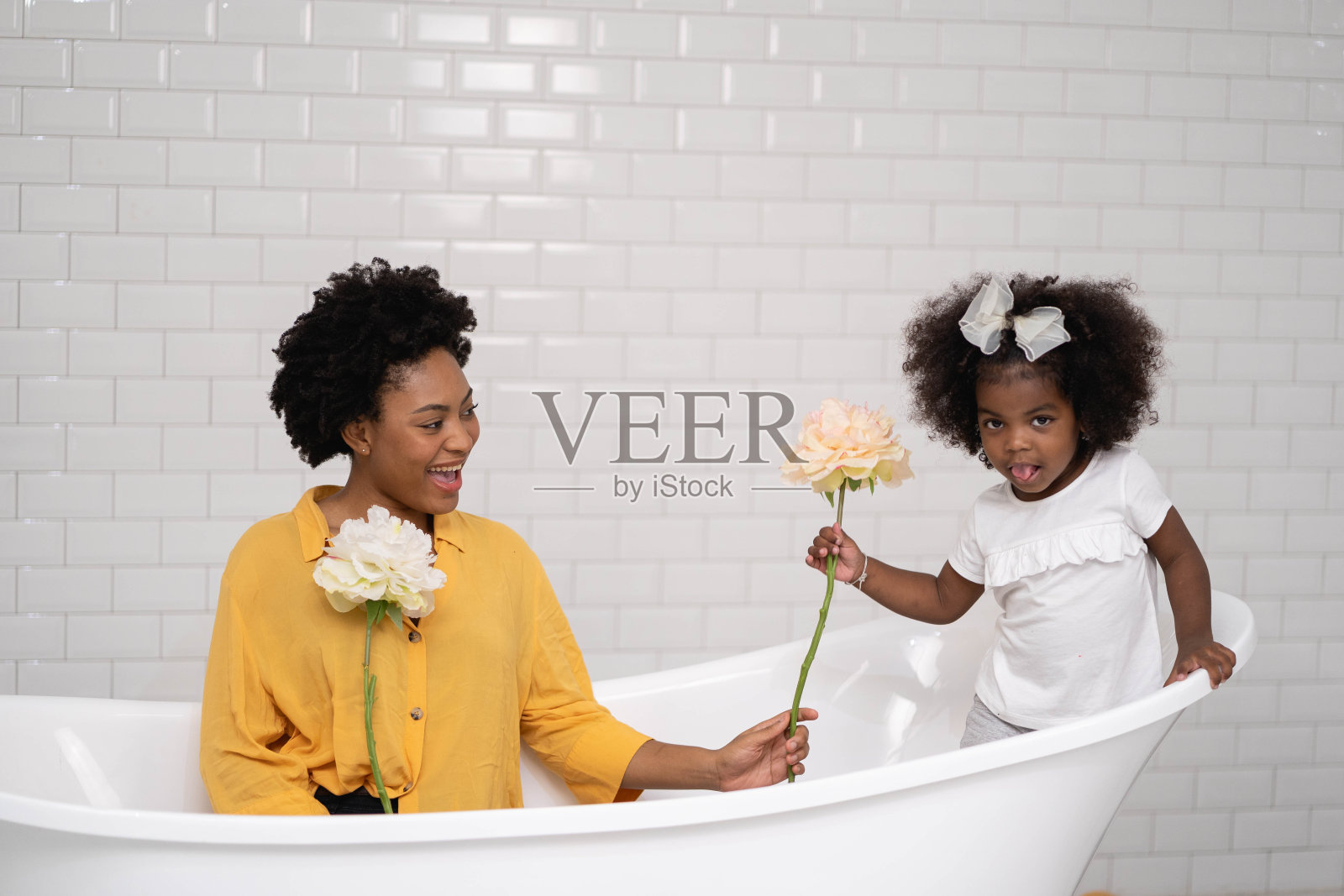 非裔美国家庭，快乐的母亲和宝贝女儿玩在一起的浴室，白色的墙壁背景照片摄影图片