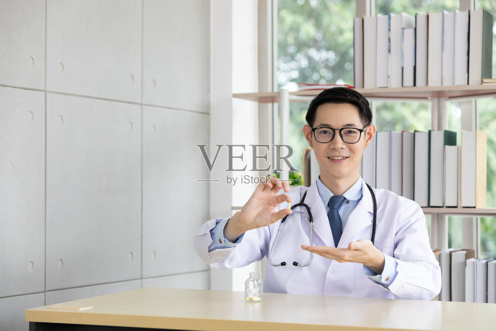 亚洲医生展示的小玻璃瓶维他命胶囊或药物，用于展示病人和处方药物前解释如何食用照片摄影图片