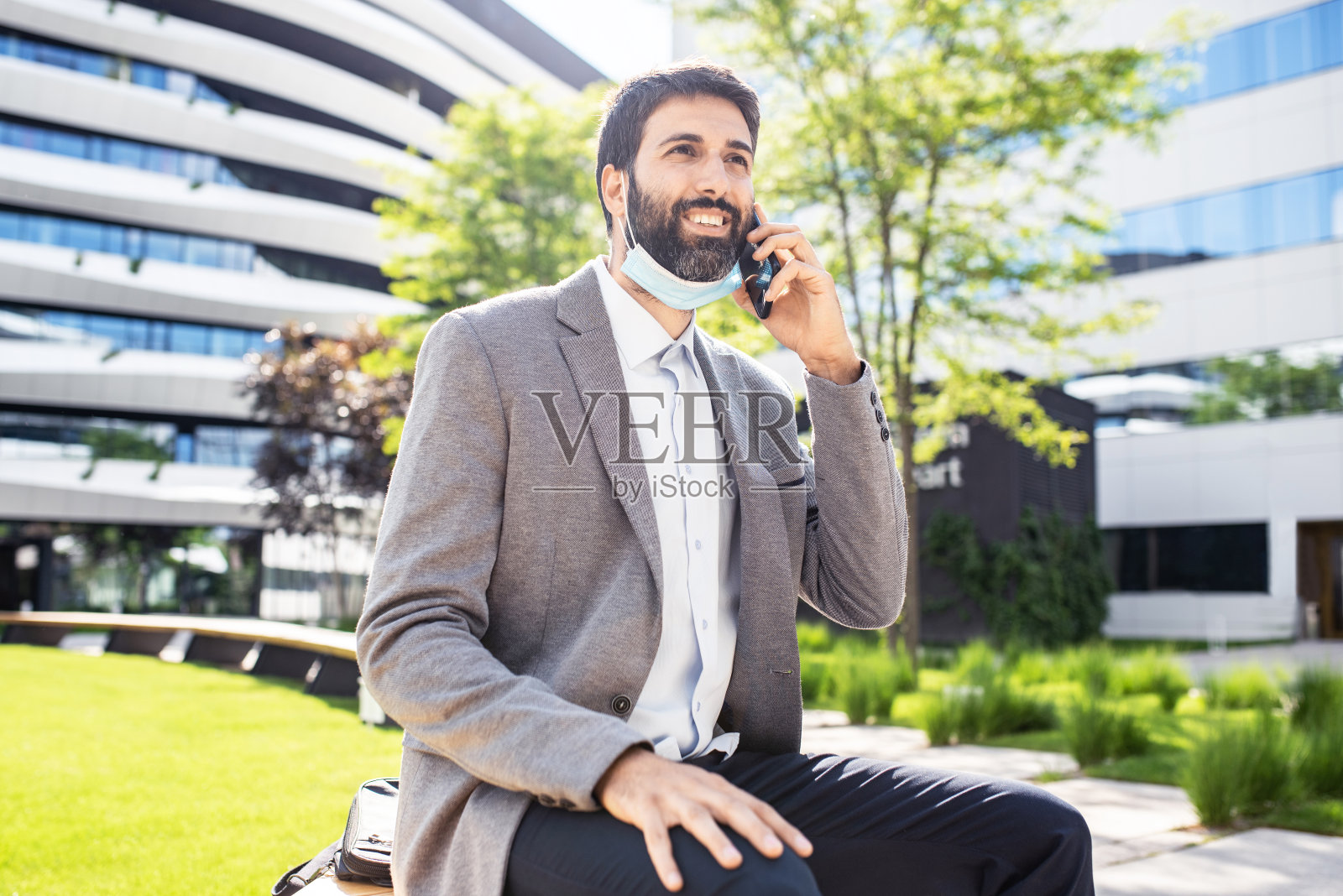 一名商人戴着口罩在商业区打电话照片摄影图片