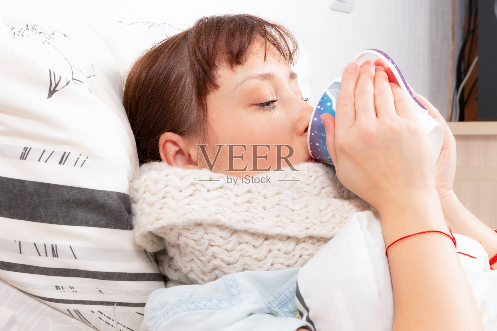 年轻漂亮的女孩是病在家里的床上喝热姜茶照片摄影图片