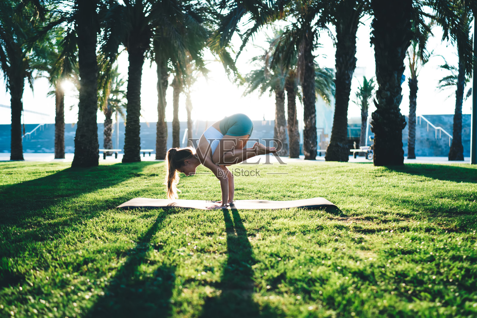 柔韧的女人在公园的瑜伽垫上做瑜伽照片摄影图片