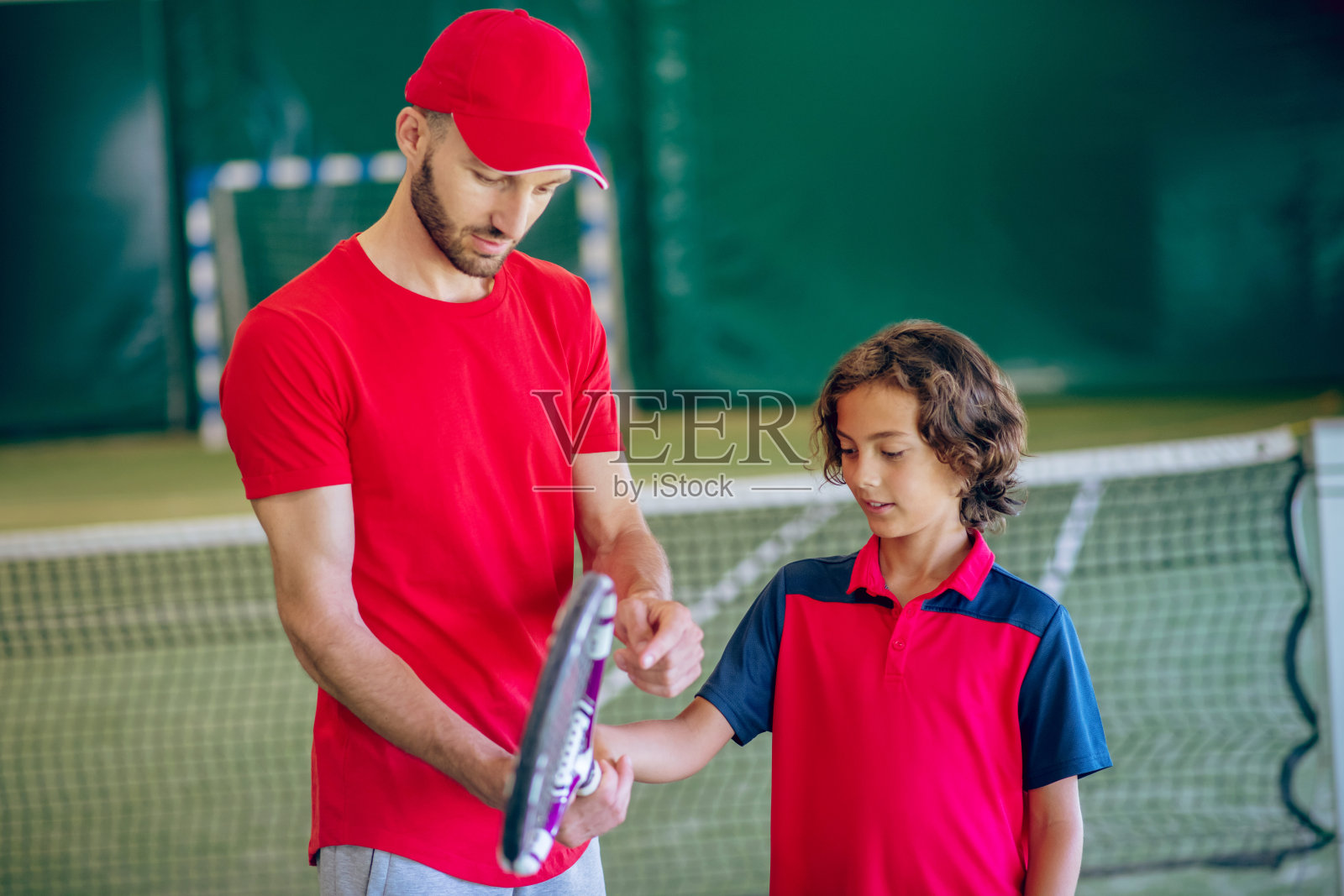 男网球教练教一个男孩如何拿球拍照片摄影图片