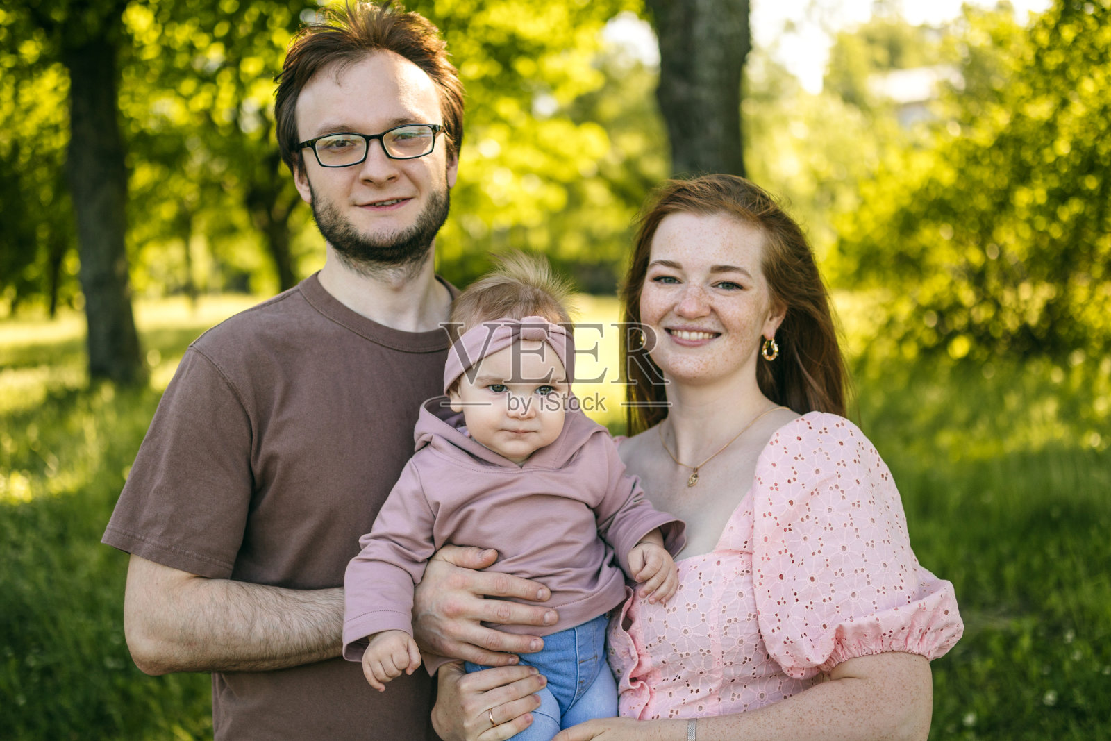 一个年轻的家庭带着一岁的孩子在公园里散步照片摄影图片