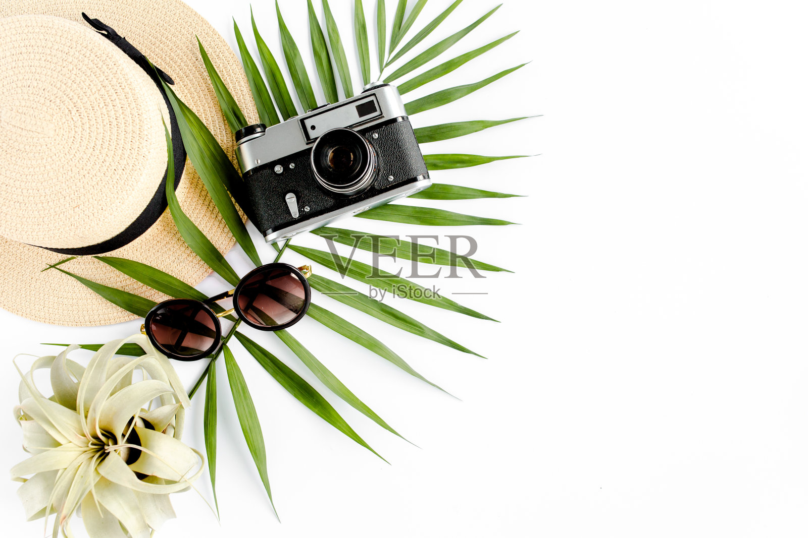 平躺旅行者配件在白色背景与复古相机，草帽，太阳镜，热带棕榈叶。旅游概念背景照片摄影图片