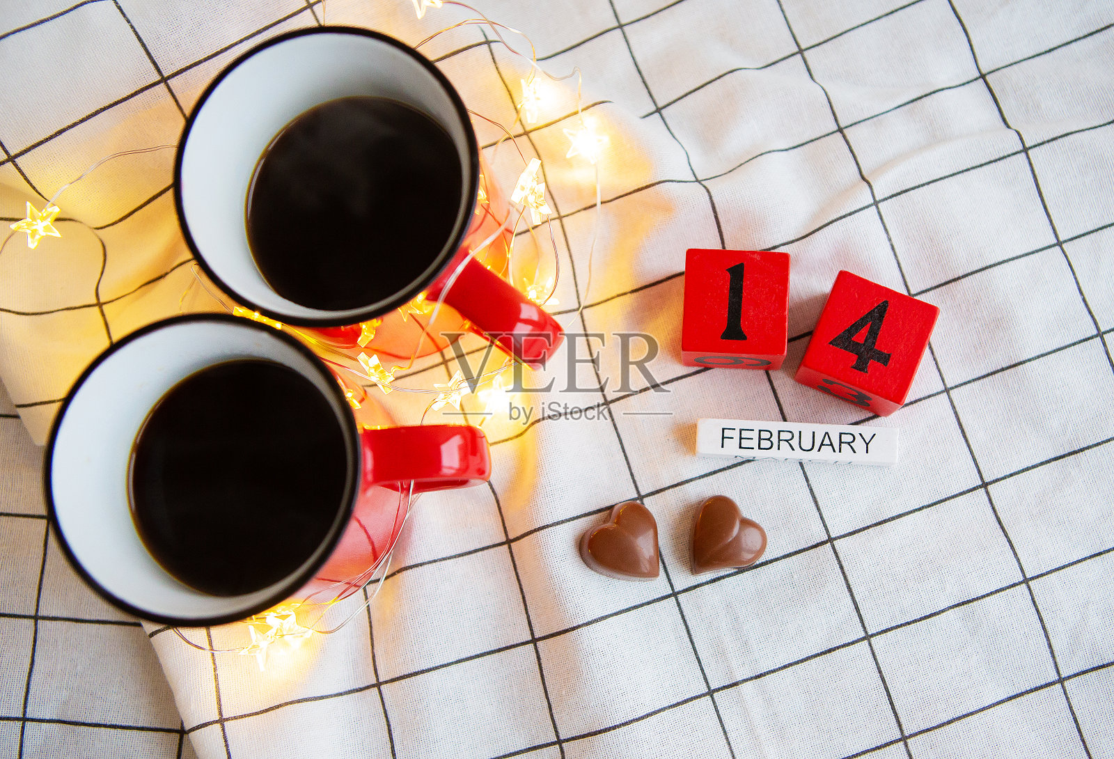 两杯红杯咖啡，背景是心形的巧克力。情人节早晨的惊喜。从以上观点。照片摄影图片