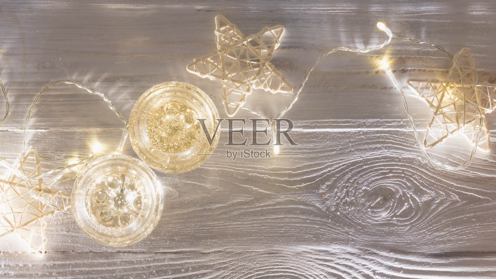 香槟杯，发光的花环，白色木制圣诞背景上的白色星星照片摄影图片