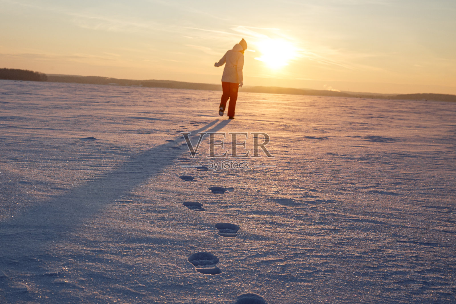雪地里的近距离脚印。女孩在夕阳西下时离开了。照片摄影图片