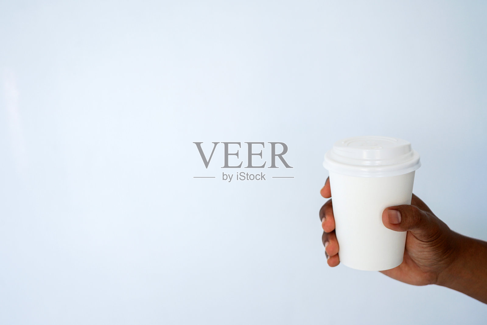 一个皮肤黝黑的男人的手拿着一个一次性的咖啡杯照片摄影图片