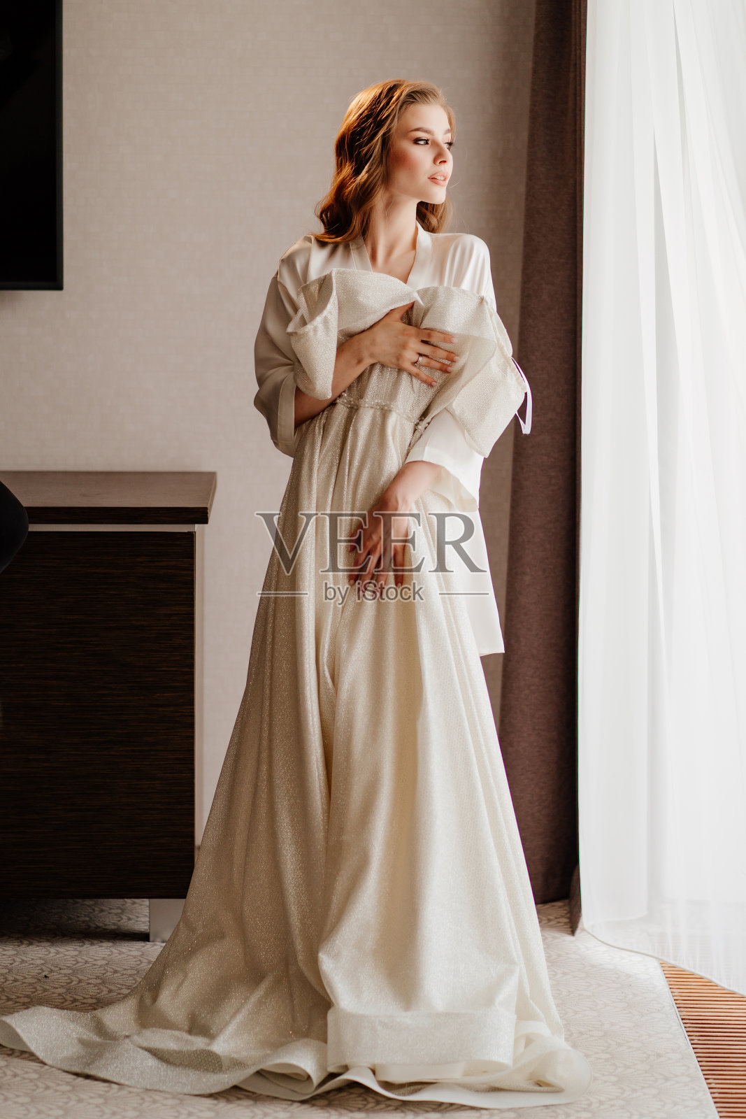 美丽的女人穿着白色长袍，手里拿着婚纱在她面前照片摄影图片