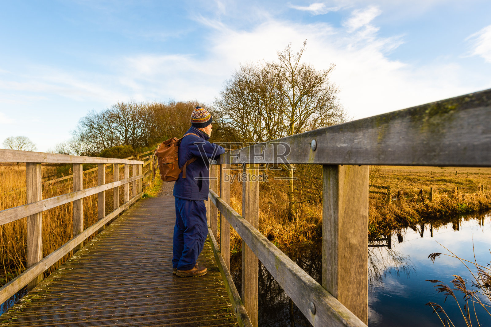 在一个晴朗的冬日早晨，一位老人独自站在一座乡间的桥上照片摄影图片