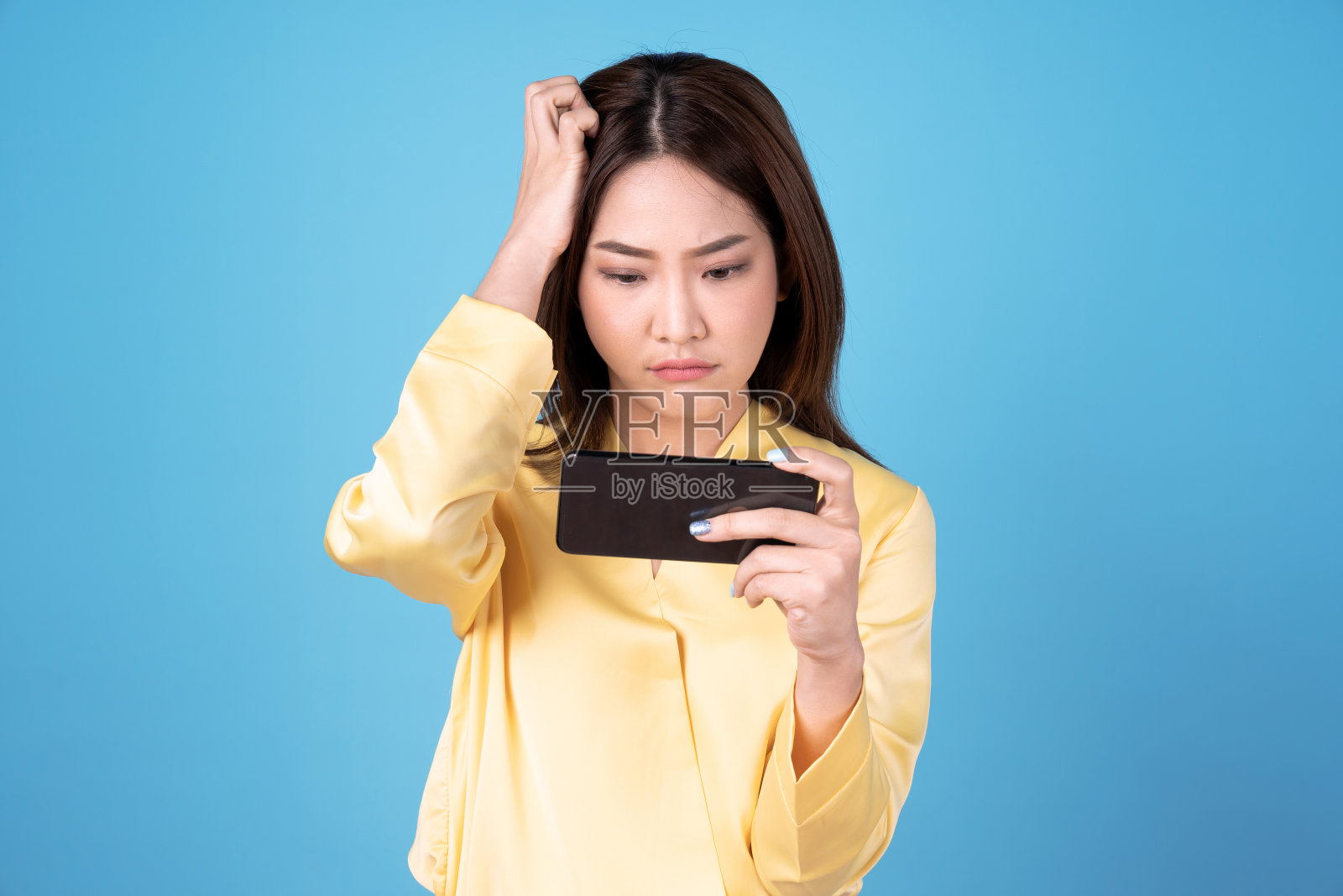 手里拿着智能手机的亚洲女性，孤立在蓝色背景下。照片摄影图片