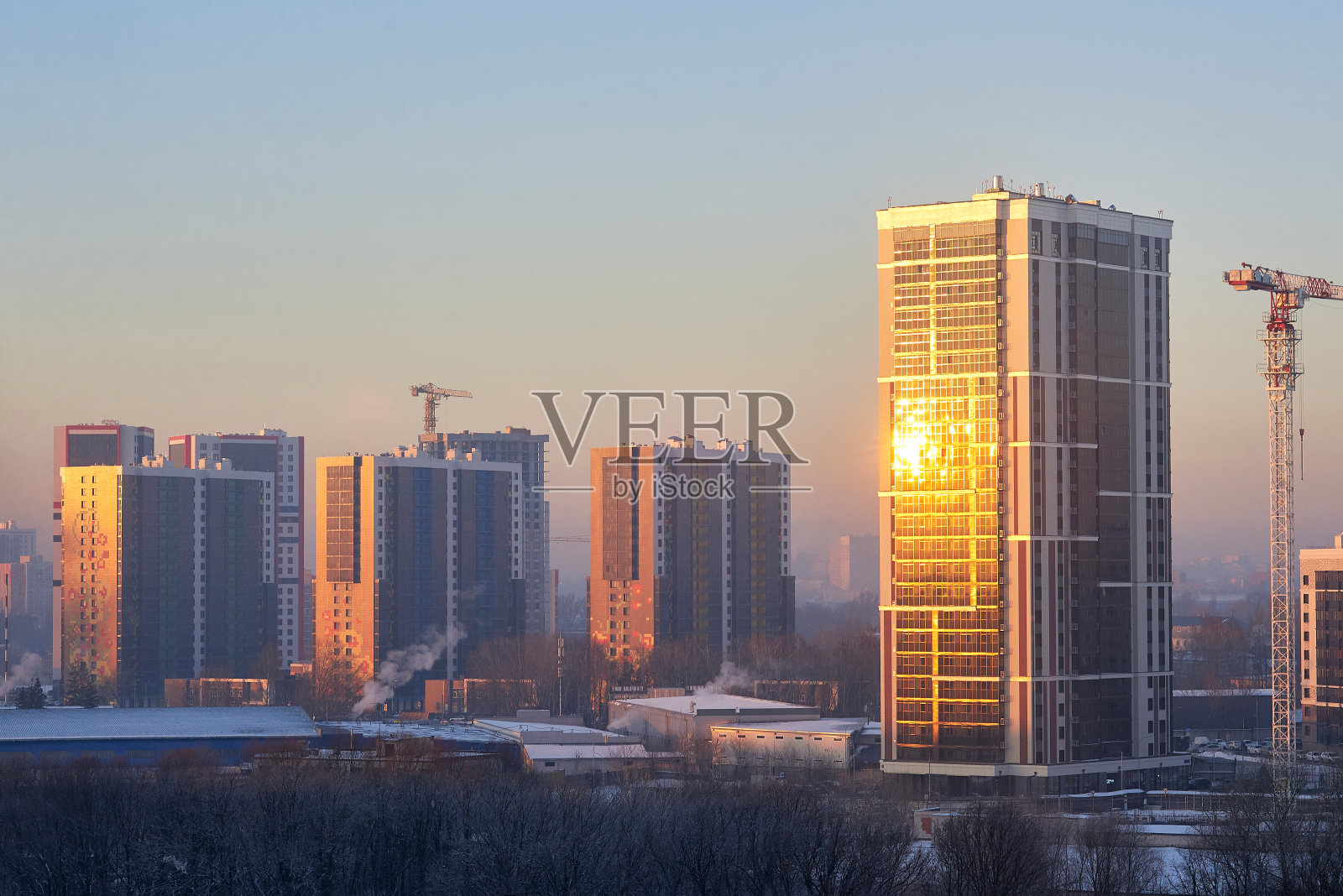 冬季日落的城市景观与新建筑，施工起重机。与复制空间。照片摄影图片