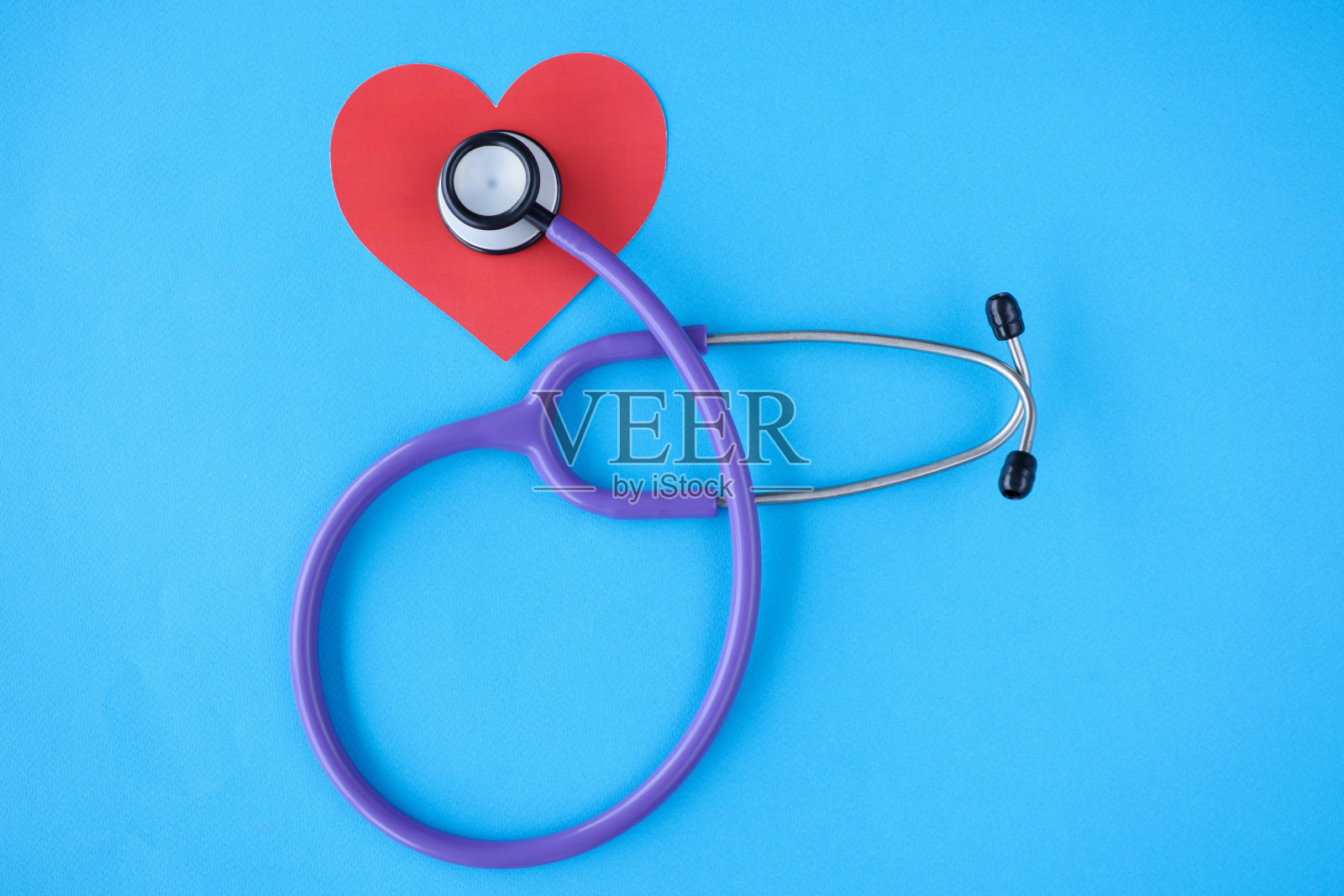 听诊器躺在蓝色背景上的红纸心上照片摄影图片