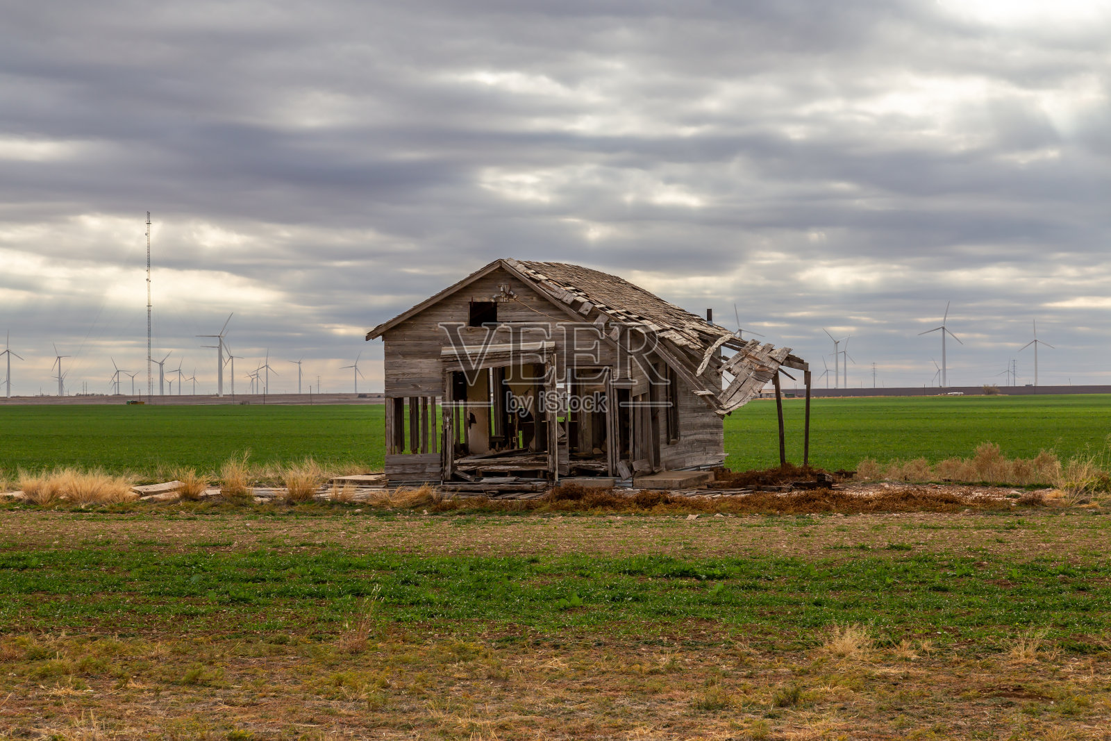农场上的废弃木屋，背景是风力发电机。照片摄影图片