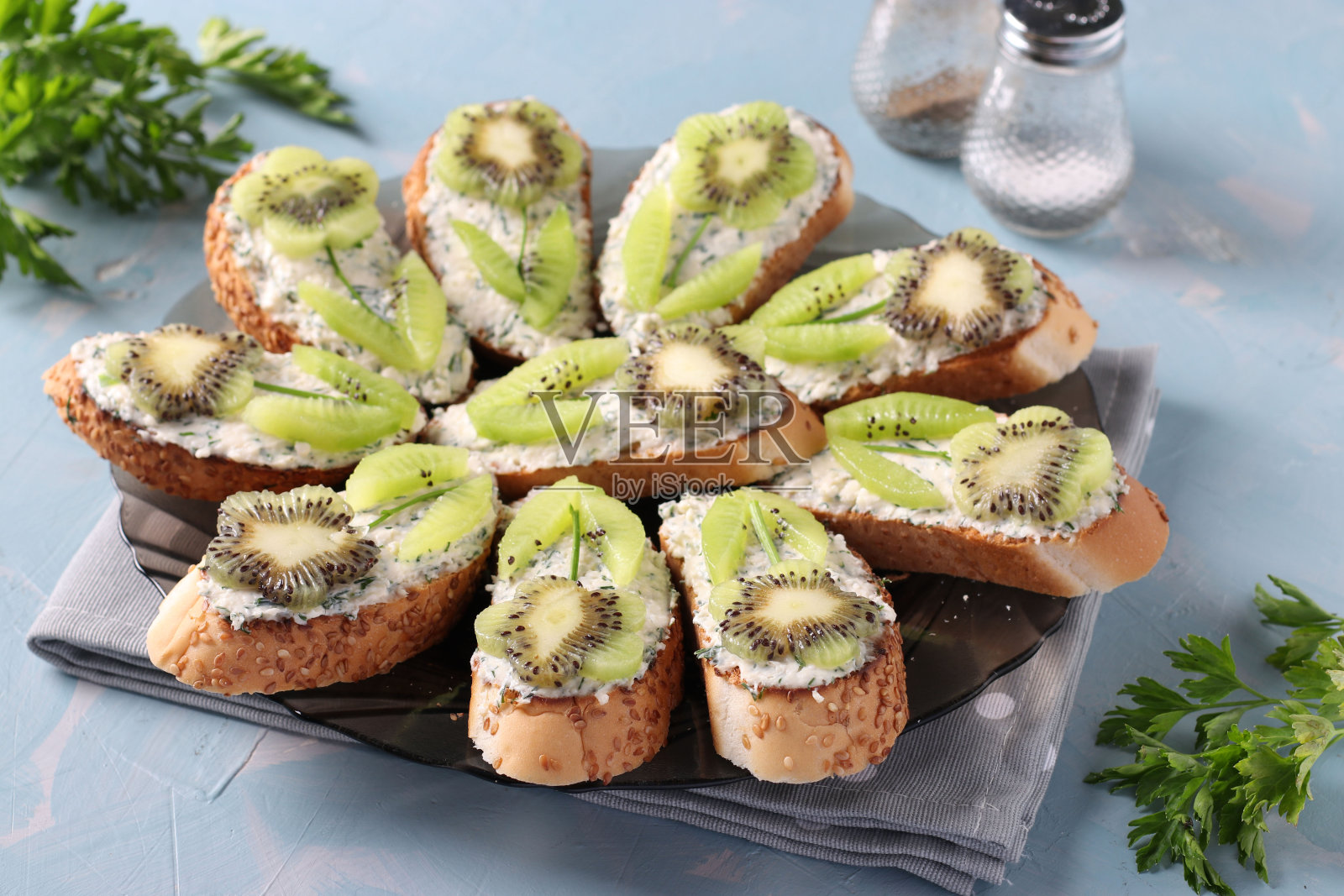 浅蓝色背景的自制奇异果、奶油芝士和大蒜三明治。特写镜头照片摄影图片