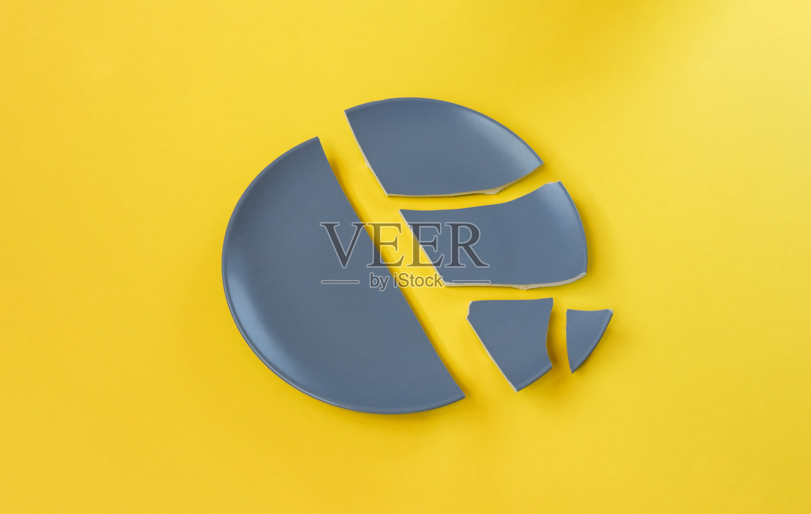 黄色背景上破碎的灰色陶瓷板。照片摄影图片