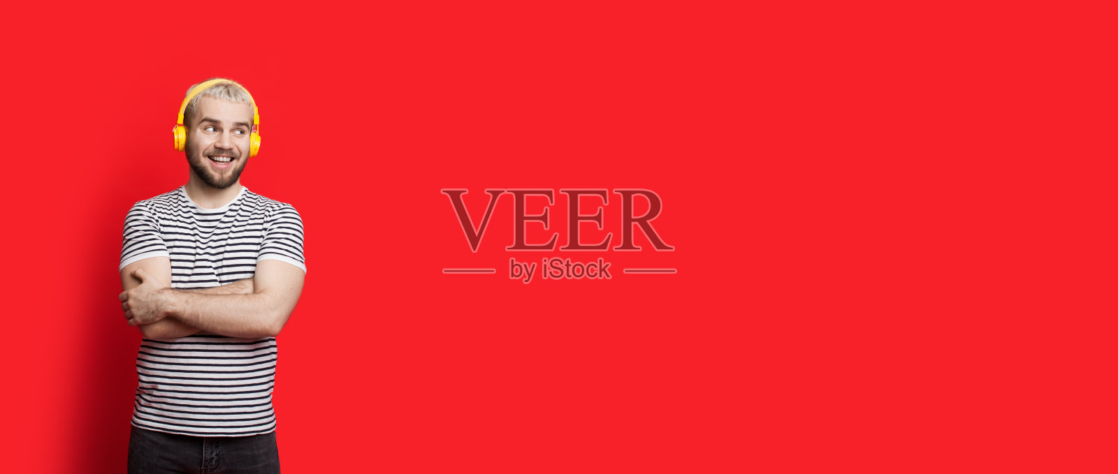 年轻的白种人，金发和胡子听着音乐，看着附近的红色自由空间照片摄影图片