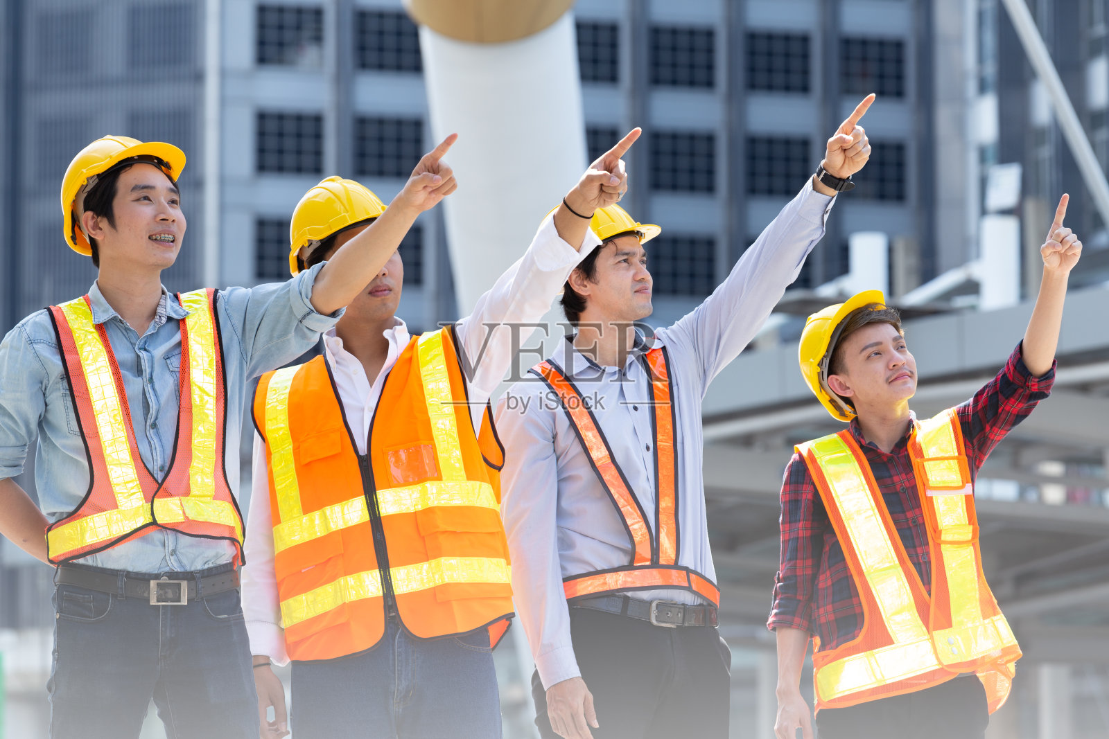 肖像施工工人或工程小组戴安全帽，安全巨大的反射器和指向工程施工与工头团队。照片摄影图片