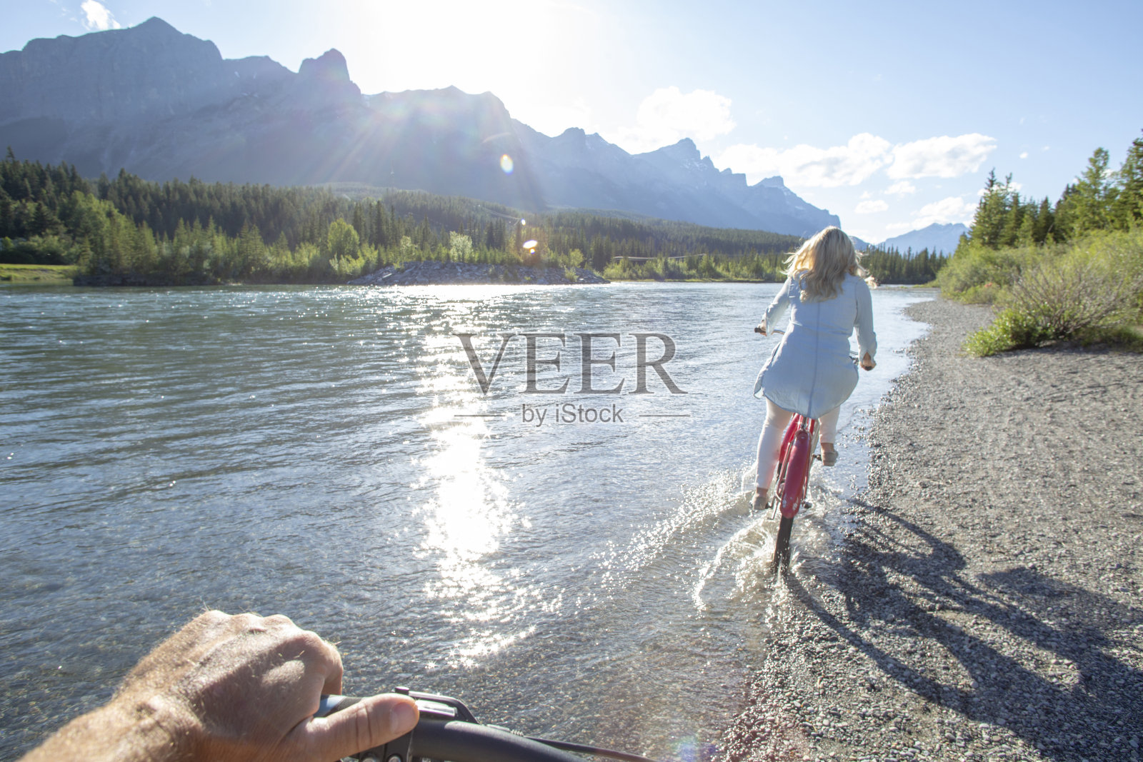 POV过去的手在河边骑着巡洋舰自行车的女人照片摄影图片