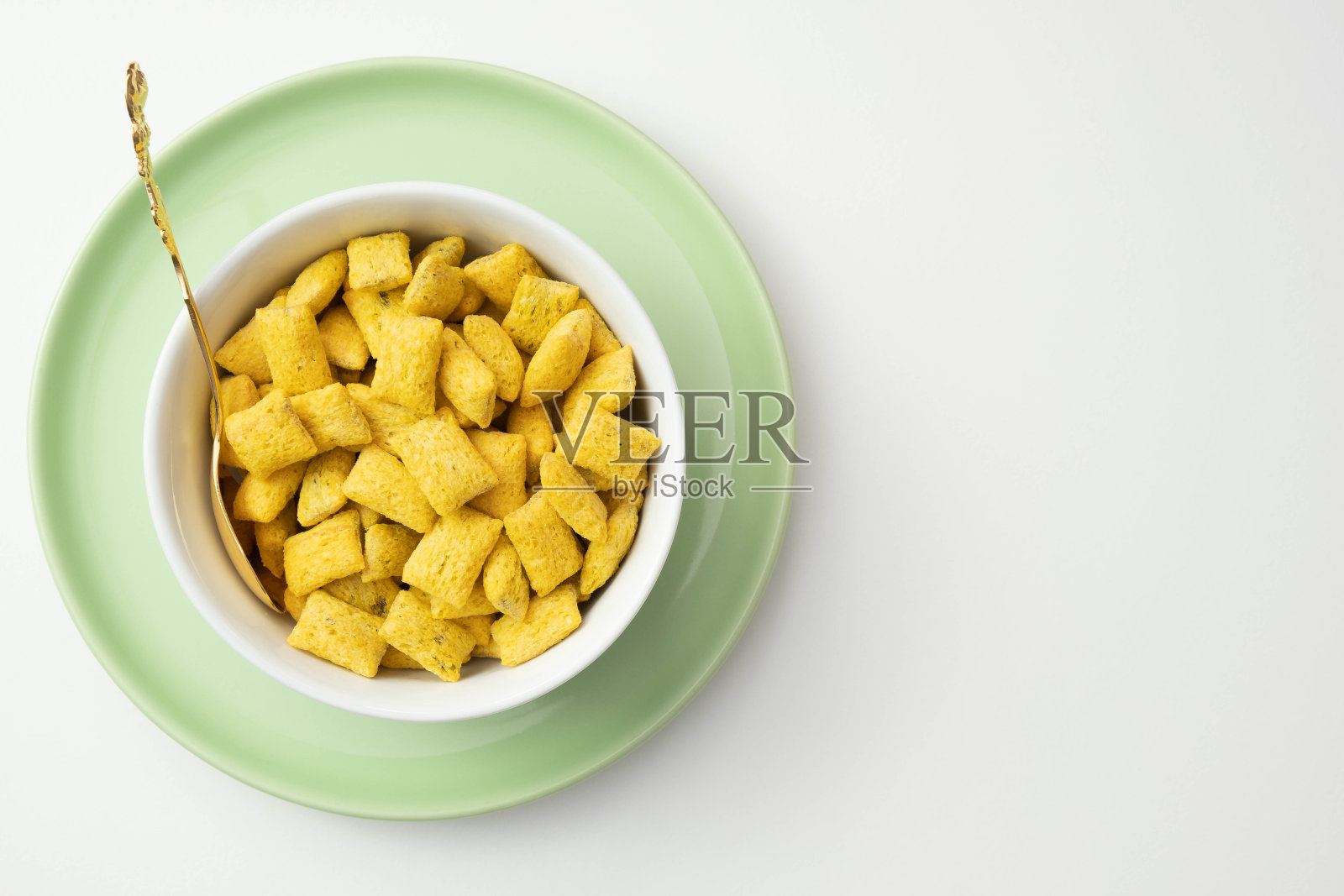 白色背景的桌子上，绿色的盘子里放着玉米片和麦片照片摄影图片