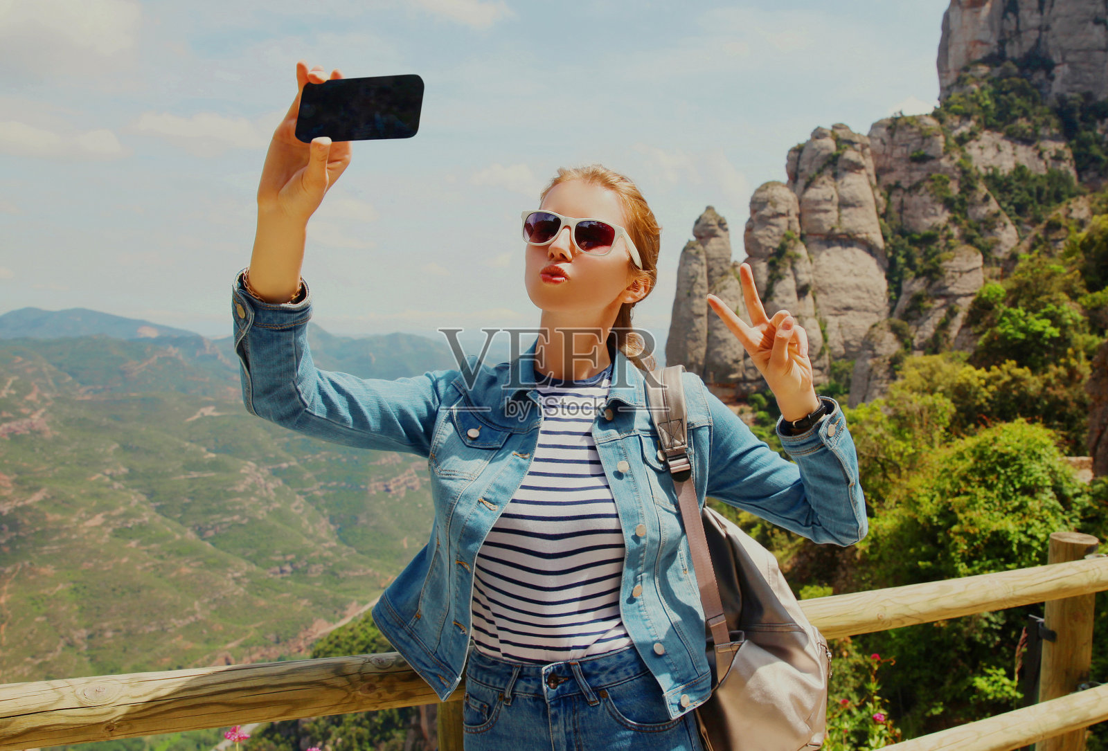 旅行图片年轻女子用智能手机在蒙特塞拉特山的背景下自拍照片摄影图片