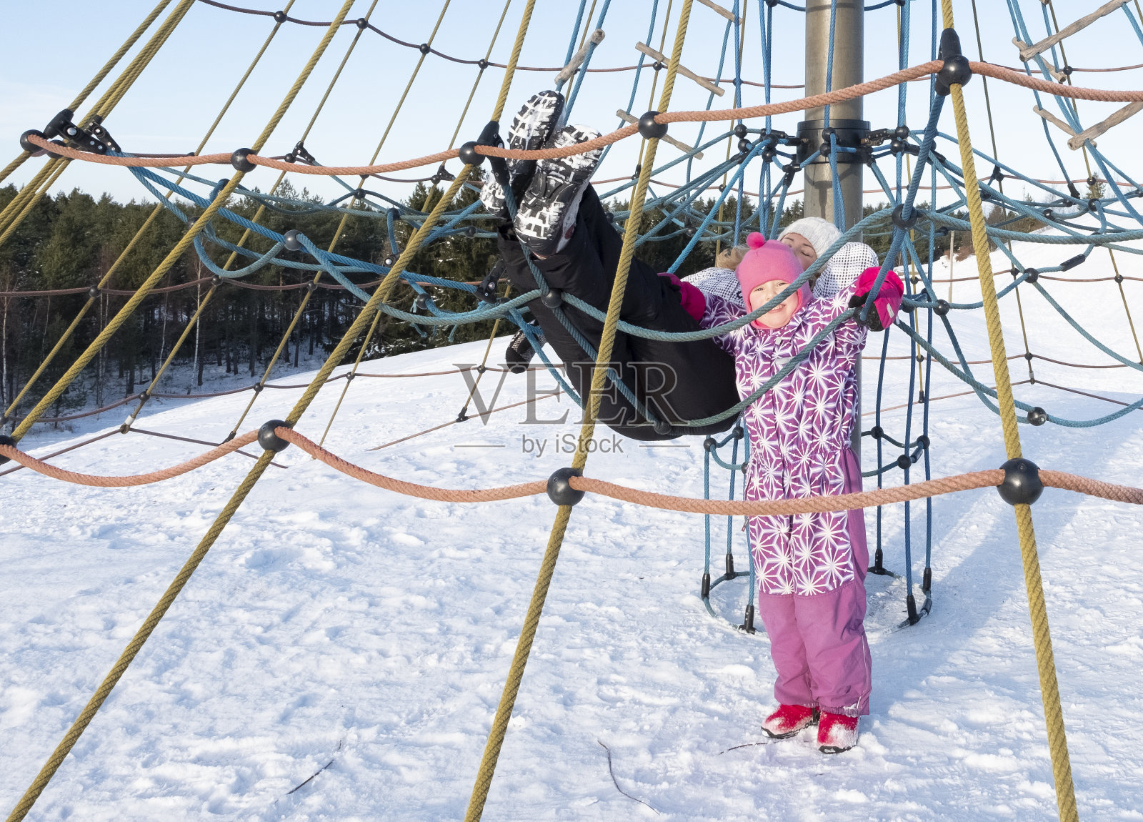 年轻的妇女和孩子，5岁的白人女孩，在操场上玩得开心。那妇人在冬日阳光的照射下晒太阳。照片摄影图片