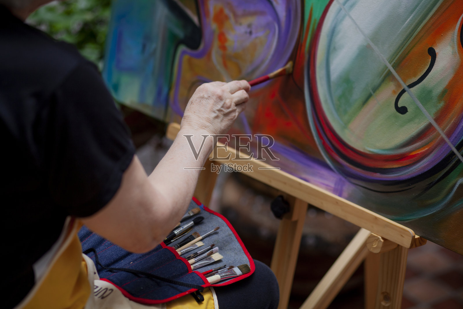 一位60岁的拉丁妇女正在自家后院画一幅美丽的画照片摄影图片