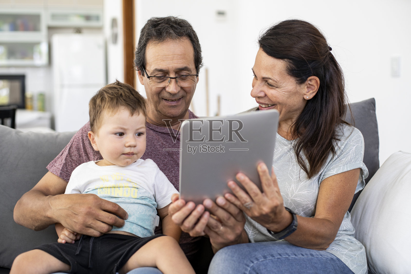 微笑的父母和他们的孙子在家里使用智能手机照片摄影图片