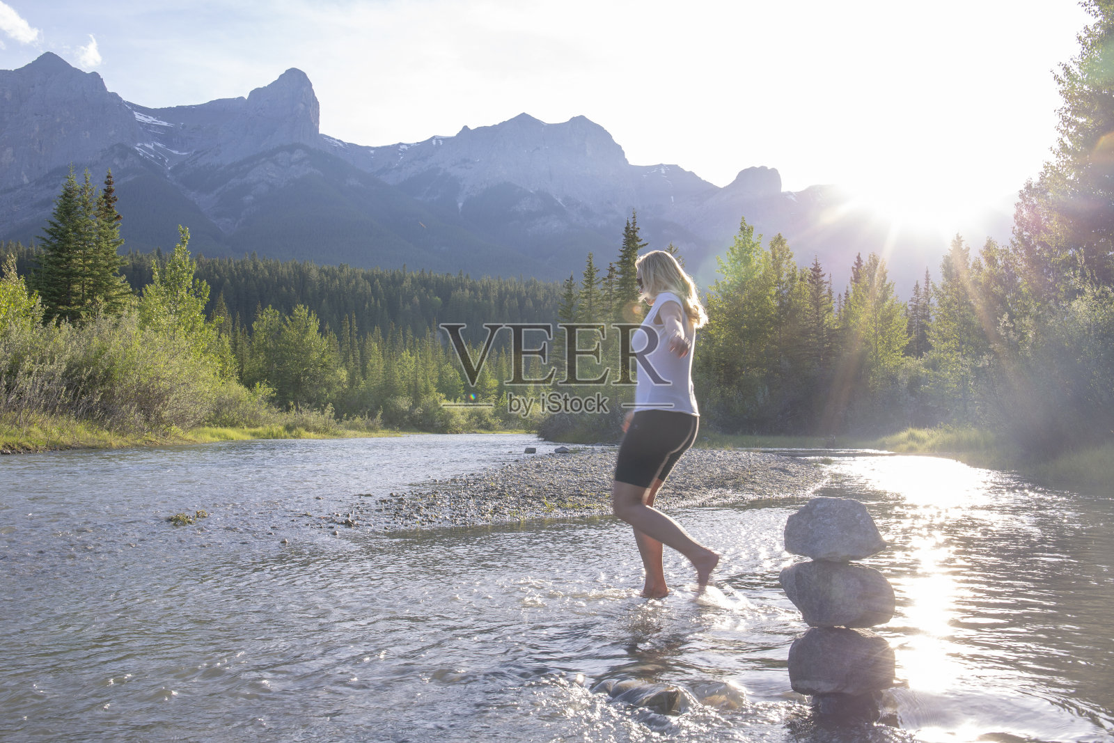 日出时分，一名女子从禅宗石旁涉水而过照片摄影图片