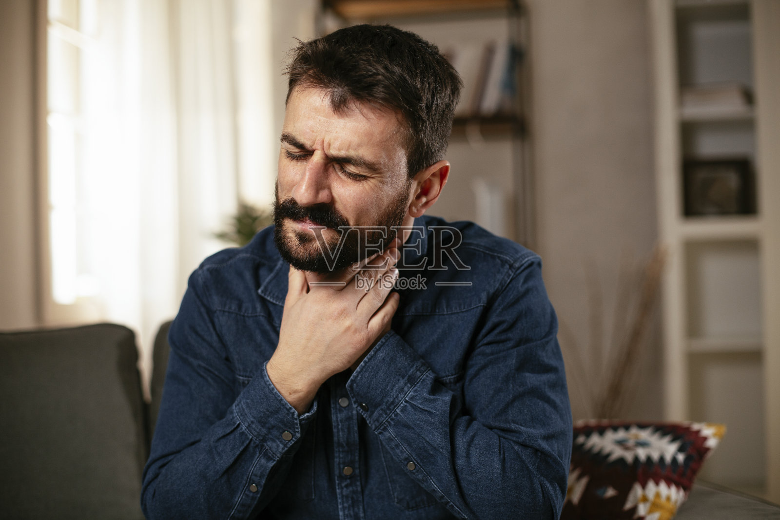 年轻人坐在沙发上发烧。照片摄影图片