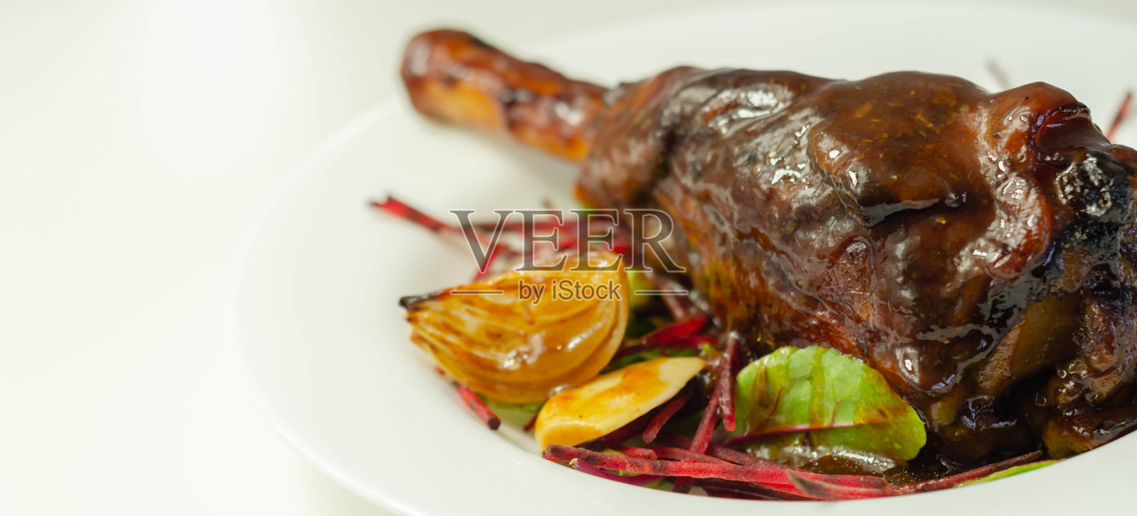 美味的羊小腿配红酒和迷迭香肉汁，配上什锦沙拉，照片摄影图片