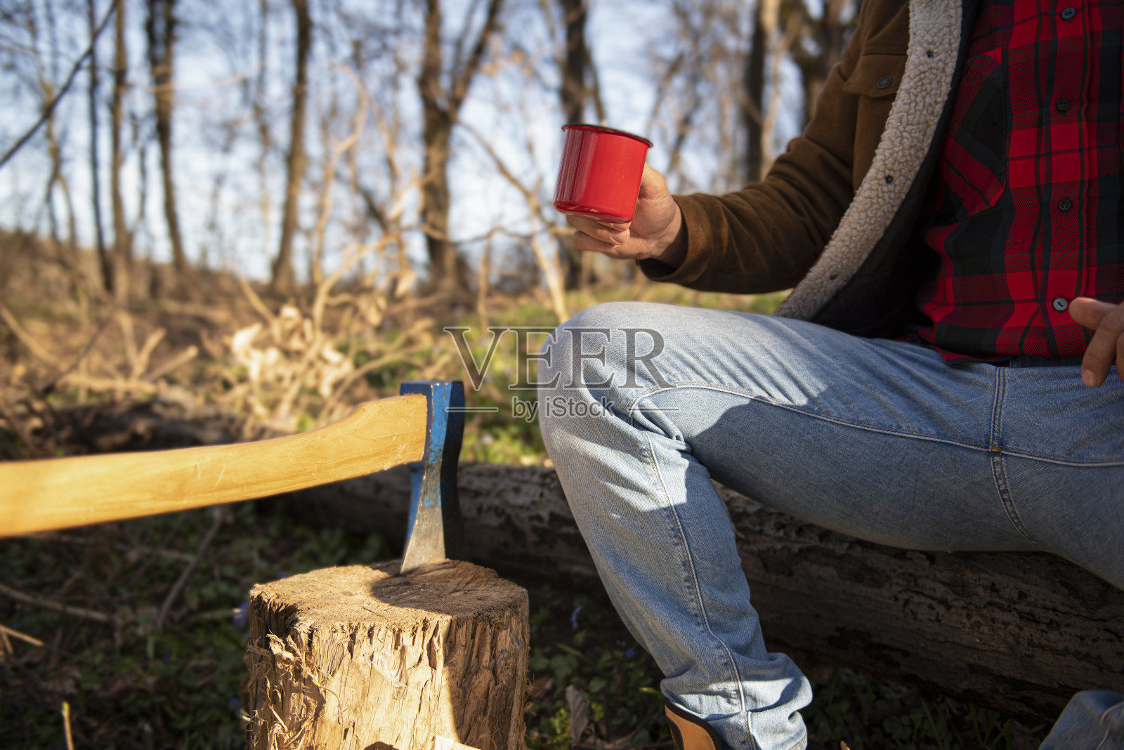 村子里一个带着斧头的大胡子男子坐在树林里休息，拍一张库存照片照片摄影图片