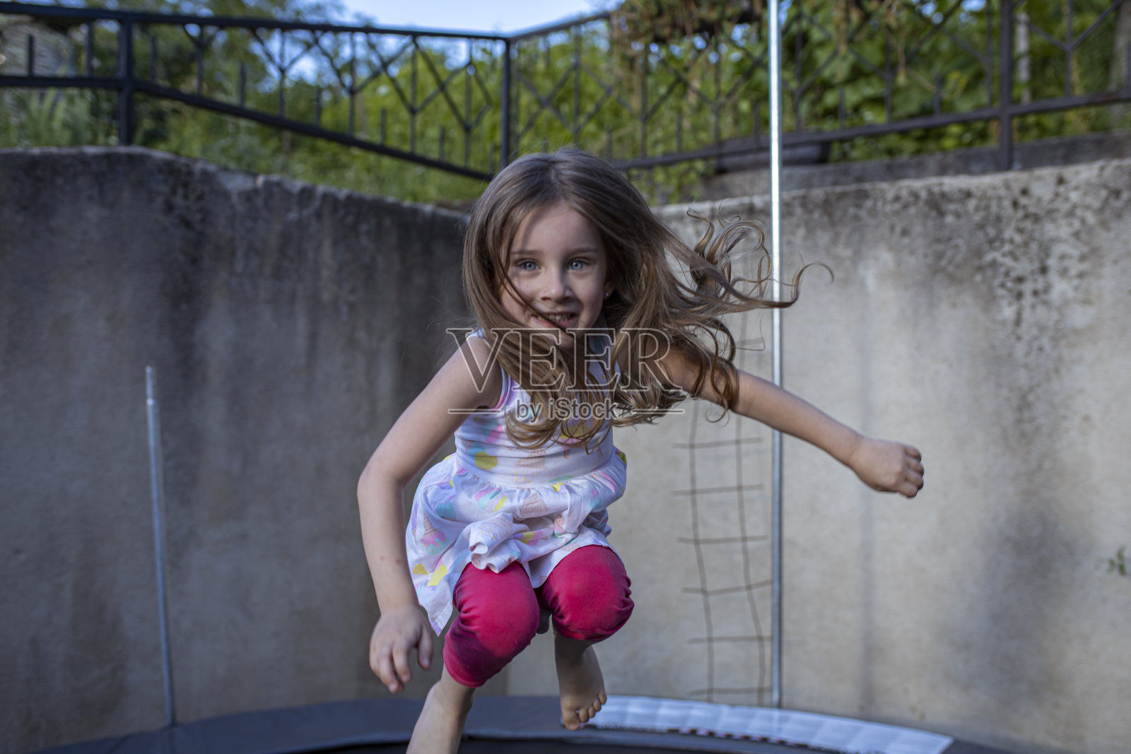 快乐的小女孩在蹦床上跳照片摄影图片