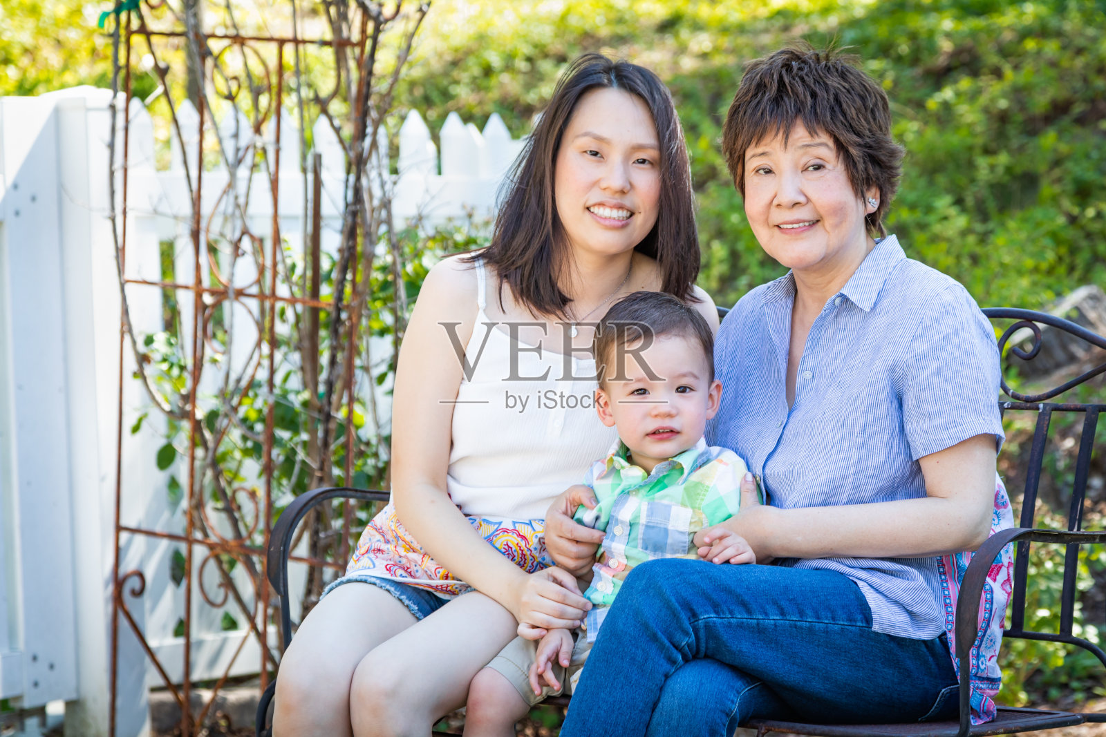 中国祖母，女儿和混血儿坐在户外长椅上照片摄影图片