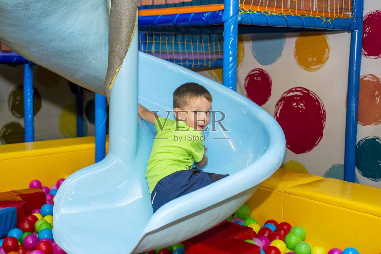 一个孩子在操场上骑在山上，玩得很开心。孩子在托儿所玩耍。照片摄影图片