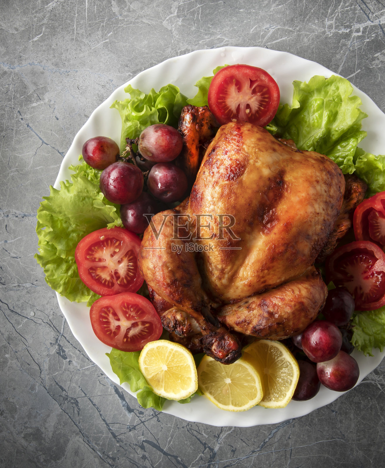 在大理石桌子上，把整只鸡、蔬菜和水果放在盘子里炸。感恩节和圣诞节的传统食物。从上往下看。照片摄影图片