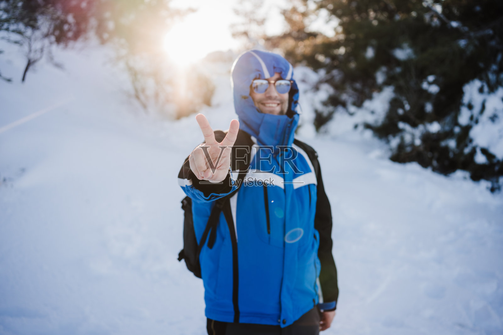 夕阳下的雪山，快乐的帅哥。旅行和户外运动的概念。冬季照片摄影图片