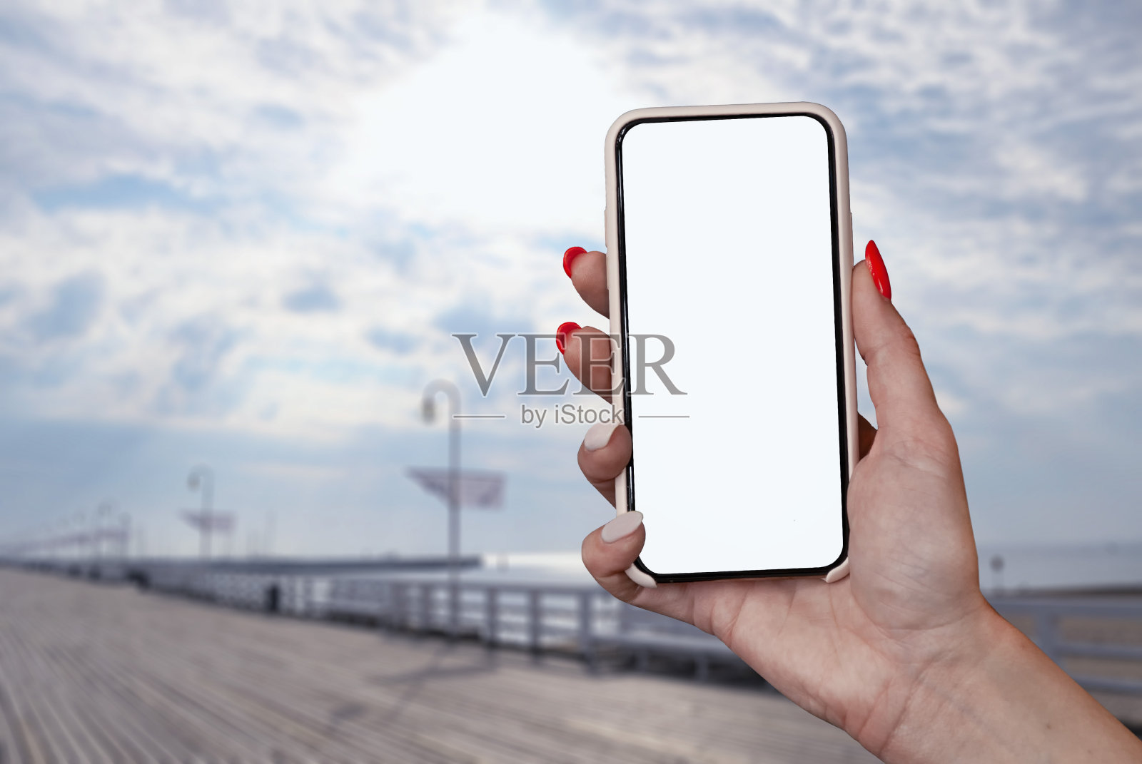 女孩手里拿着一个智能手机的特写镜头，白色的屏幕上是大海的背景。模拟技术。照片摄影图片