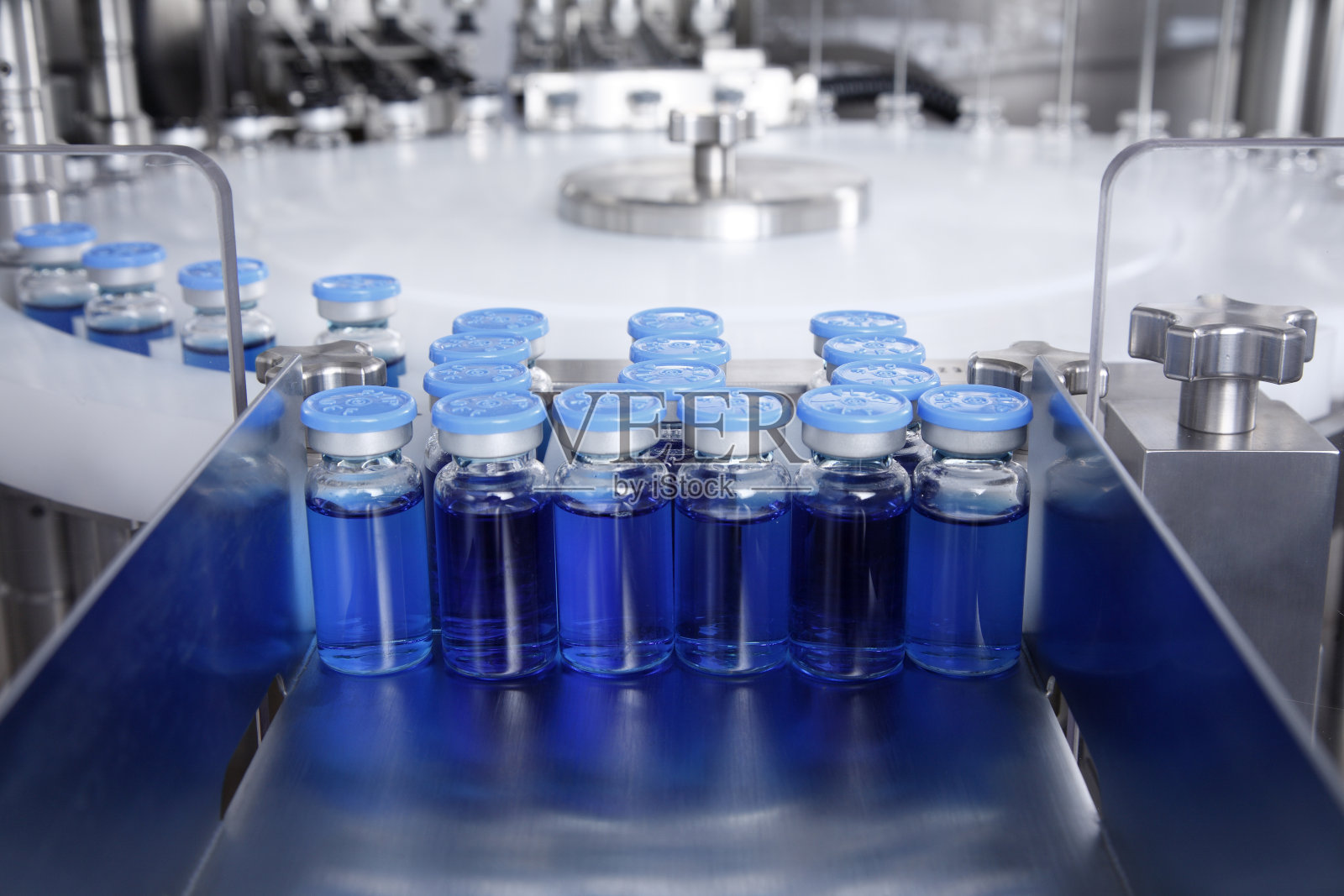 在生产的玻璃瓶托盘上有一个自动液体分配器，用于灌装抗菌病毒药物、抗生素和疫苗的流水线照片摄影图片