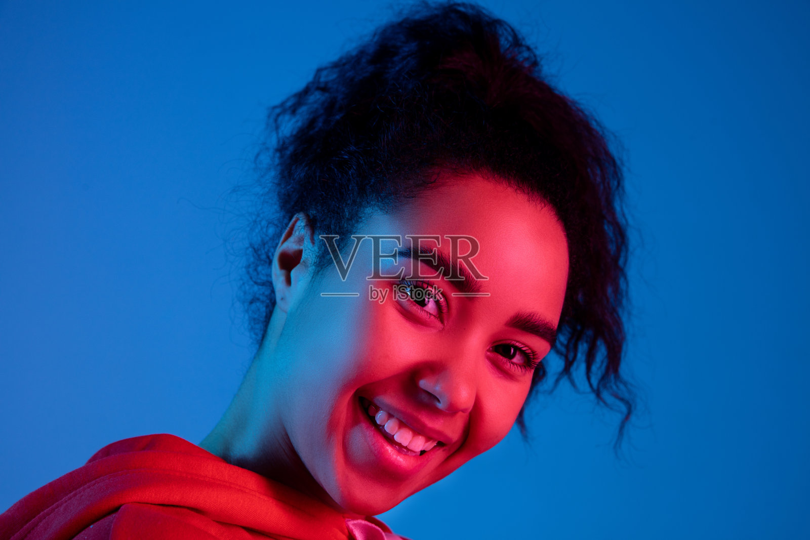 非裔美国妇女的肖像被隔离在彩色霓虹灯下的蓝色画室背景上照片摄影图片