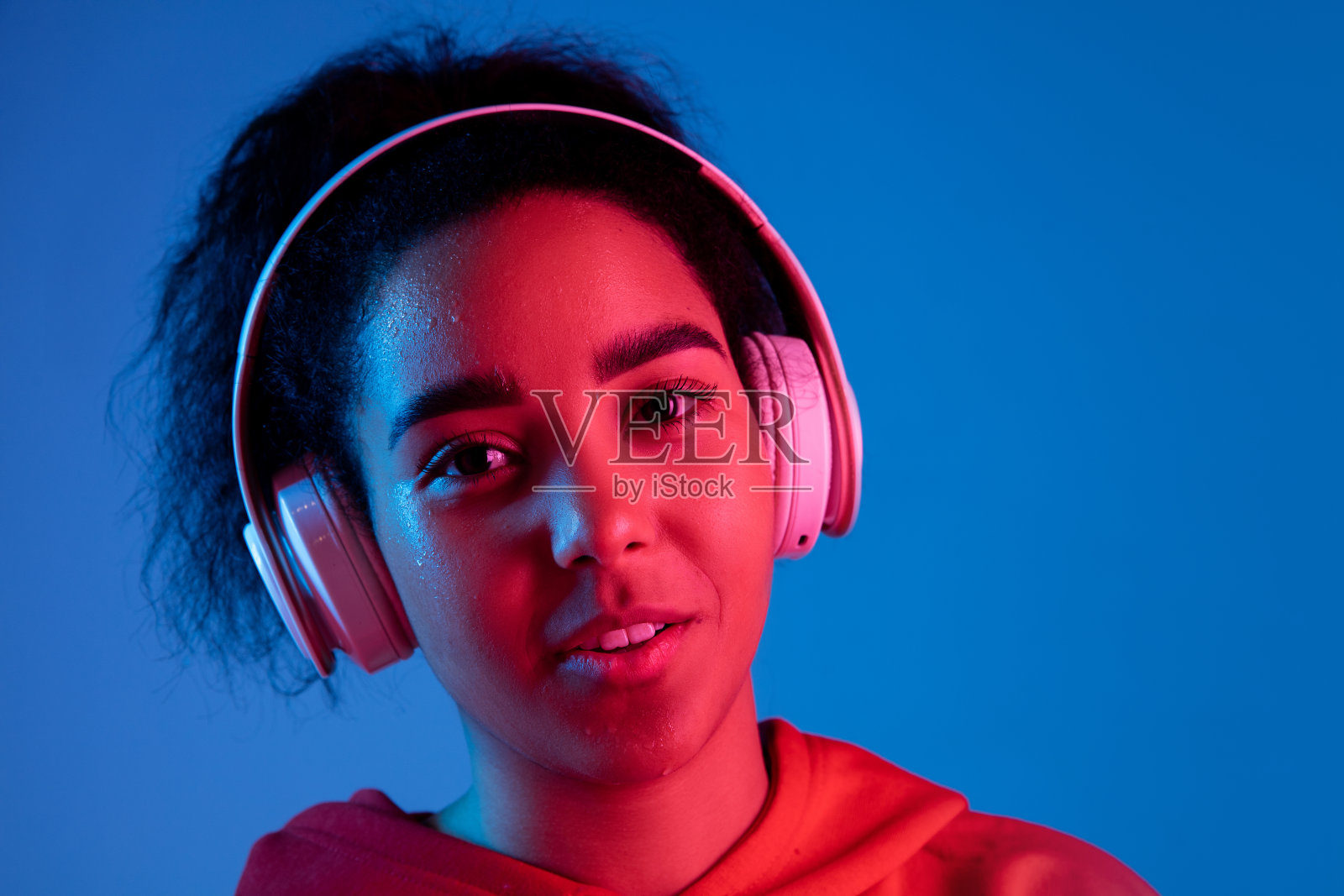 非裔美国妇女的肖像被隔离在彩色霓虹灯下的蓝色画室背景上照片摄影图片