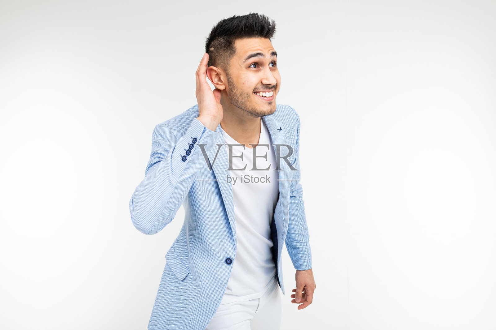 一个穿着蓝色夹克的迷人男人在白色的背景上聚精会神地听着照片摄影图片