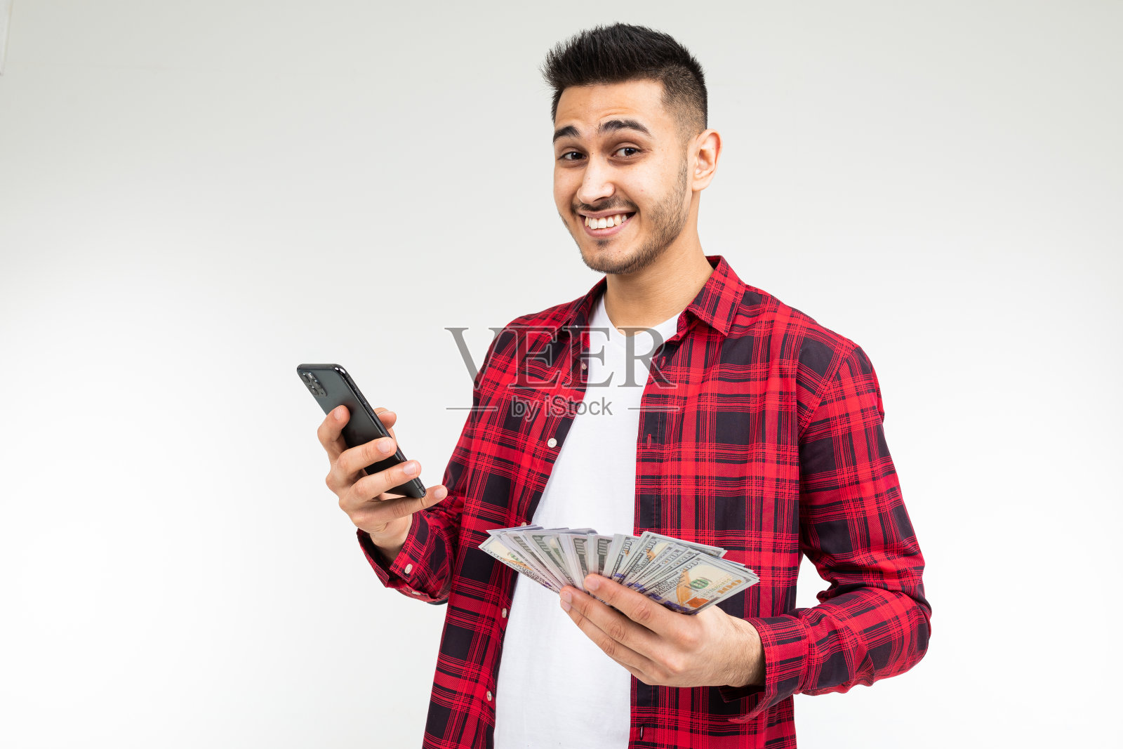 一个可爱的家伙的肖像与一堆钱在一个白色的工作室背景与拷贝空间打电话照片摄影图片