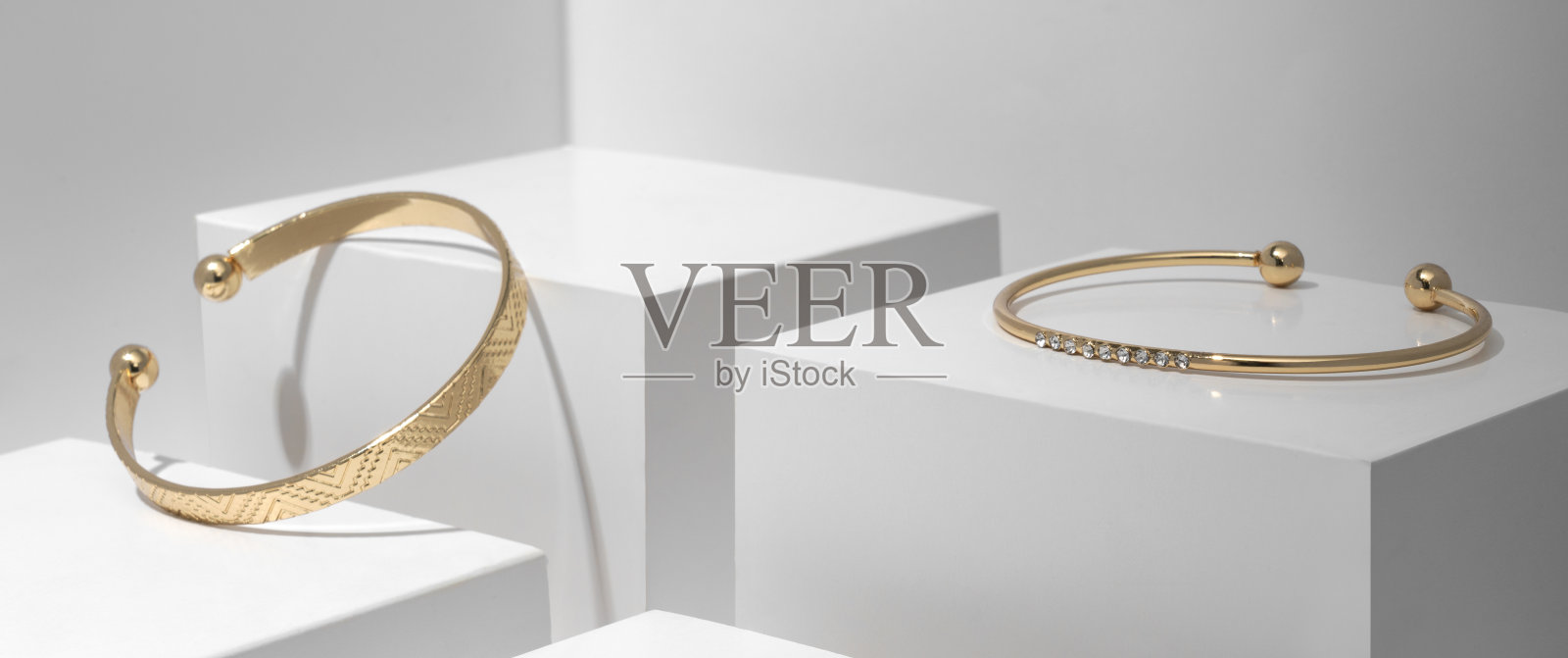 两个现代的金色手镯上的白色几何立方体照片摄影图片