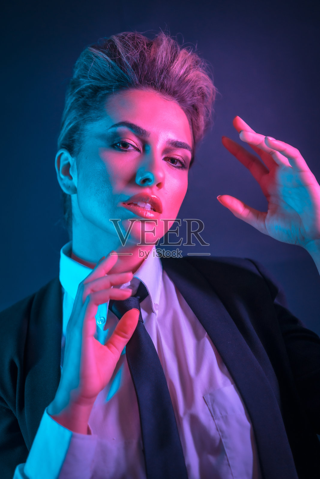 一个性感的年轻金发女在一个黑色套装摆姿势在工作室照片摄影图片